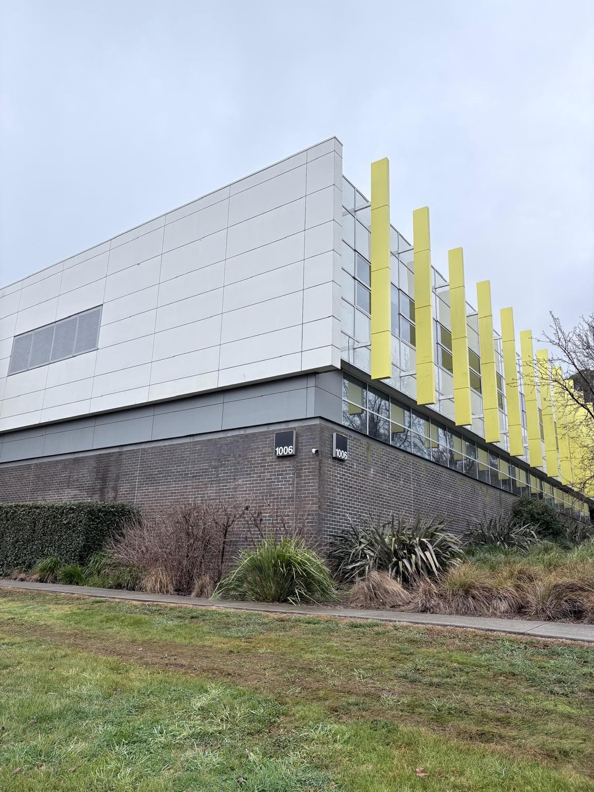 Corner of building 1006 at the Charles Sturt University Orange campus showing repainted panel cladding above a dark brick base