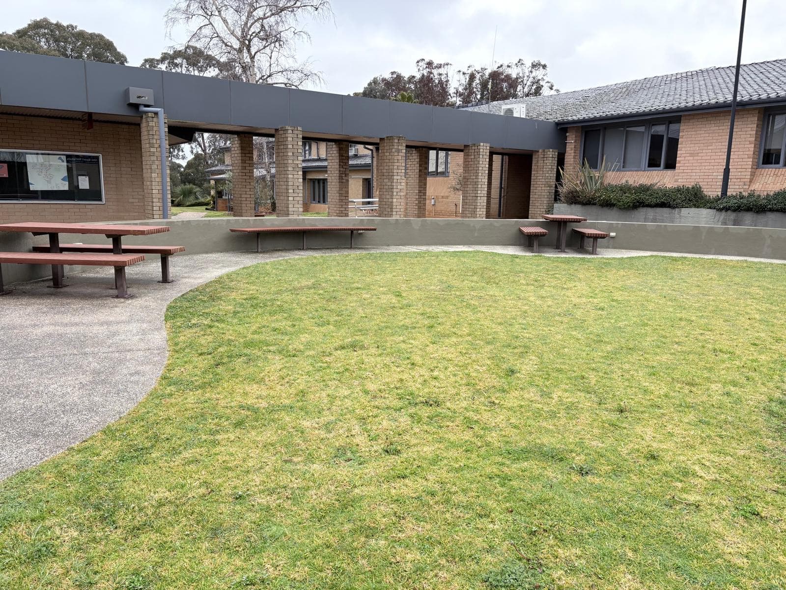 Repainted charcoal parapet above a brick colonnade at a university courtyard in Orange NSW