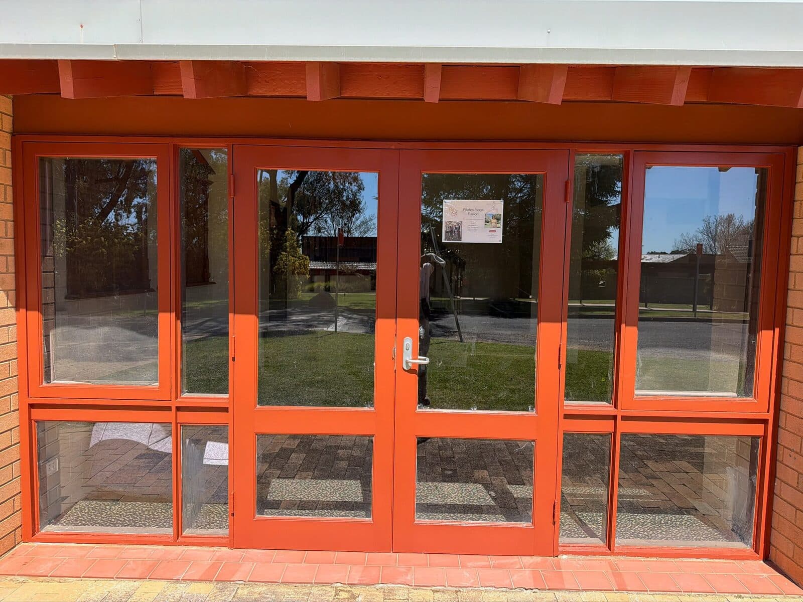 Close view of repainted orange red door frames and glazing bars at a Charles Sturt University Orange campus entry