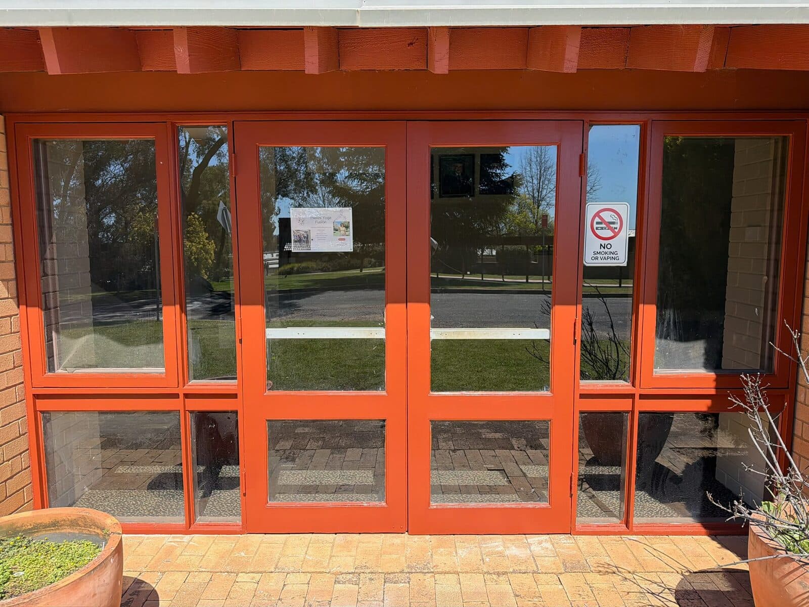 Timber framed glazed entry doors repainted deep orange red at a university campus in Orange NSW
