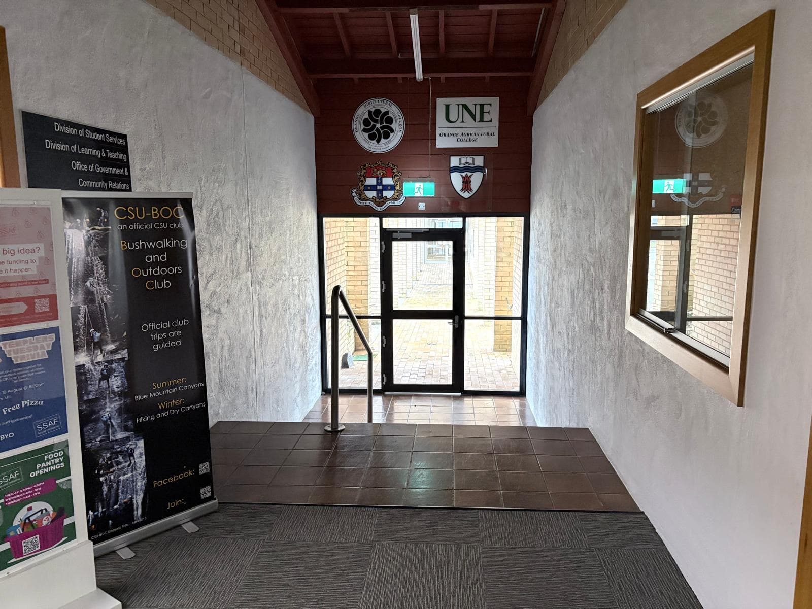 Campus entry vestibule with repainted rendered walls below an exposed timber ceiling, Orange NSW