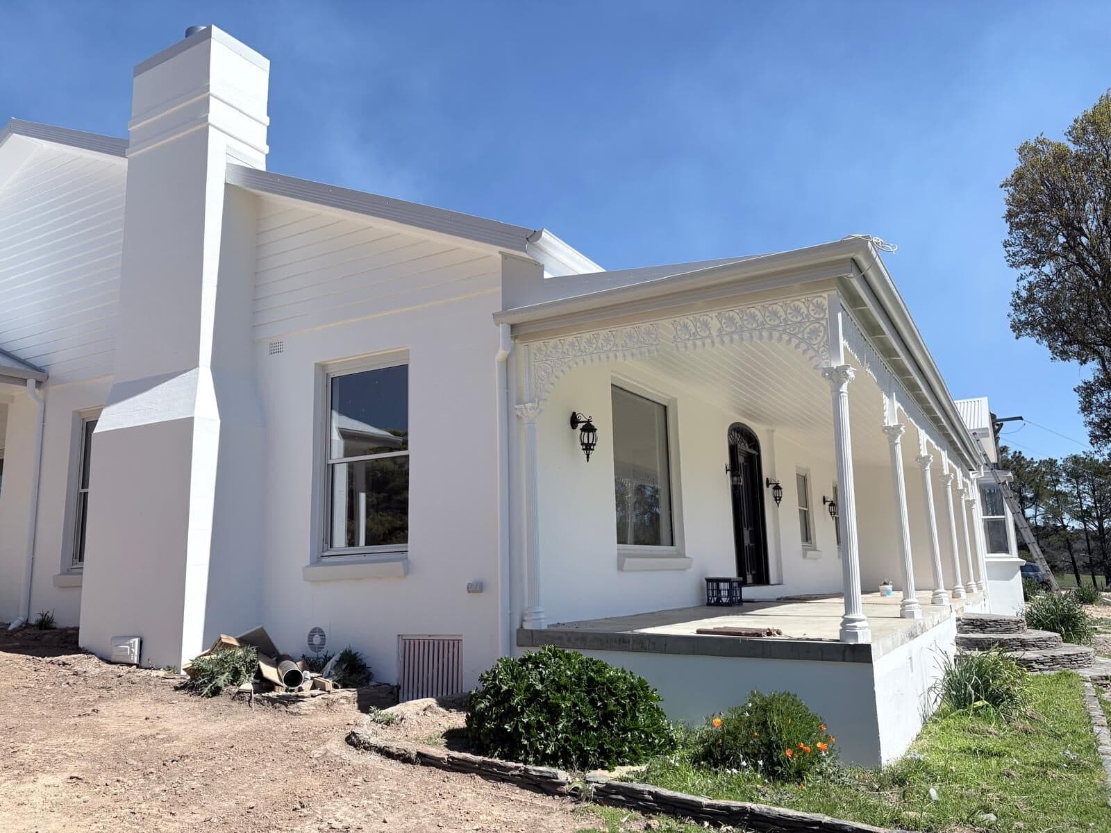 White rural homestead with a rendered chimney, lace verandah and freshly painted trim, photographed after completion, Central West NSW