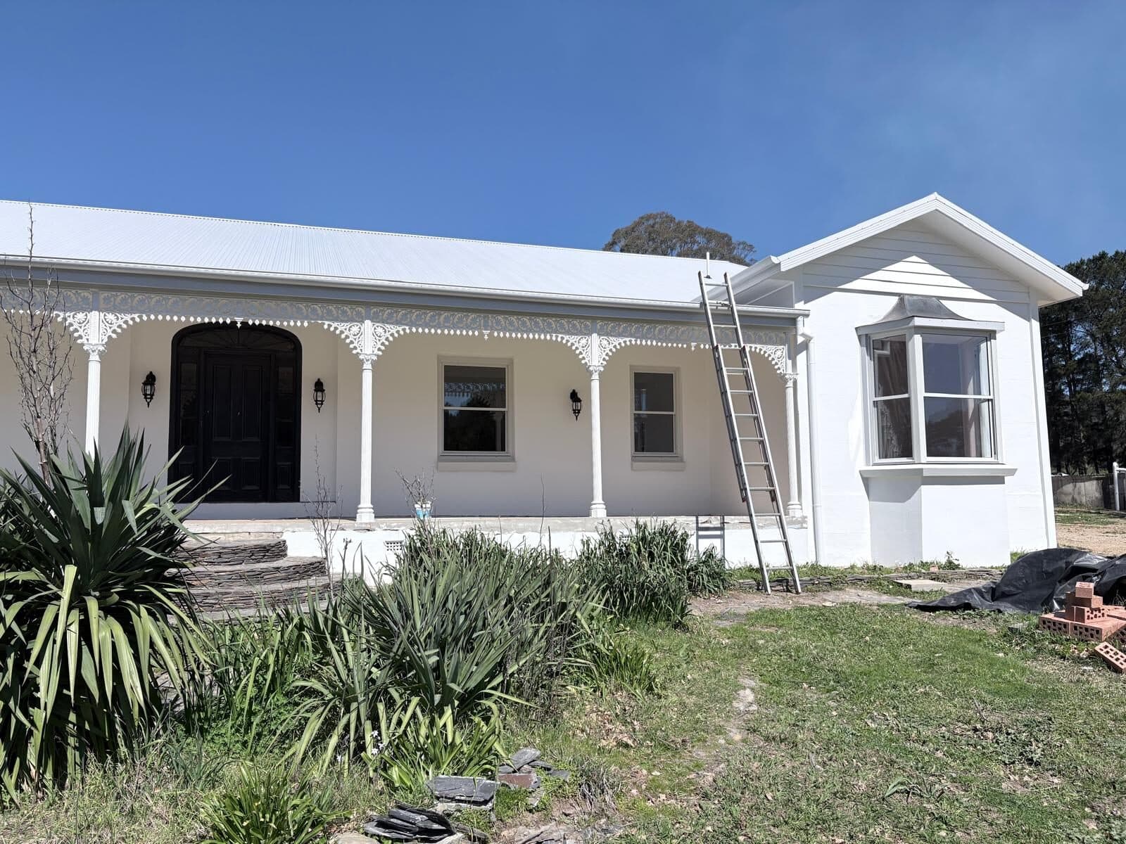 Cast iron lace brackets and a bay window on the repainted verandah of a rural homestead, Central West NSW