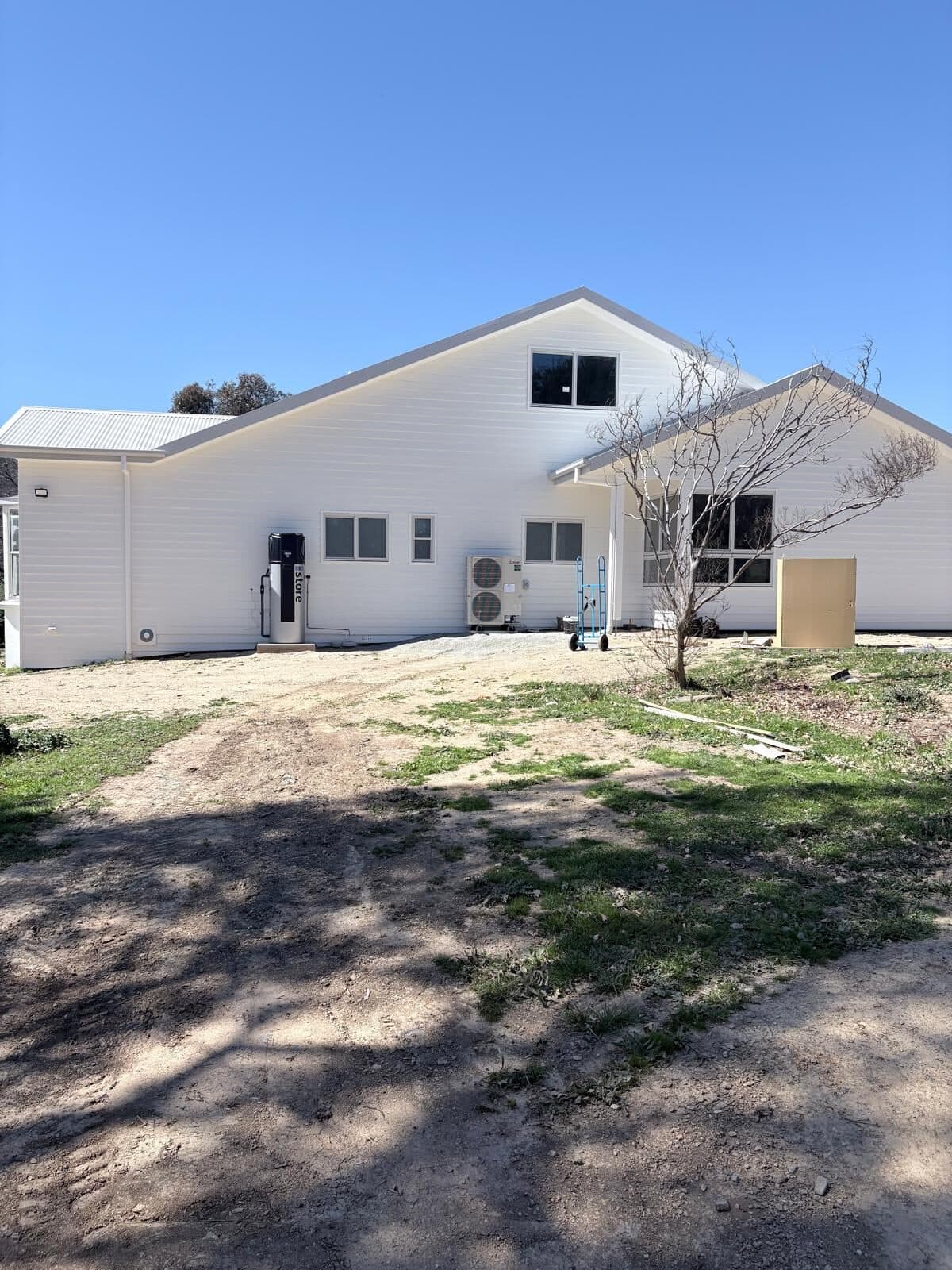 Newly built white weatherboard wing of a rural home with a pitched roof and dormer window, Central West NSW