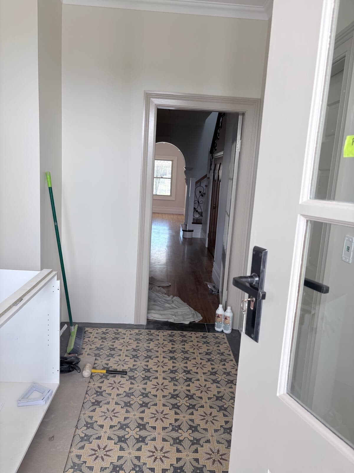 Doorway with freshly painted white architraves looking through to a hall laid with patterned encaustic tiles