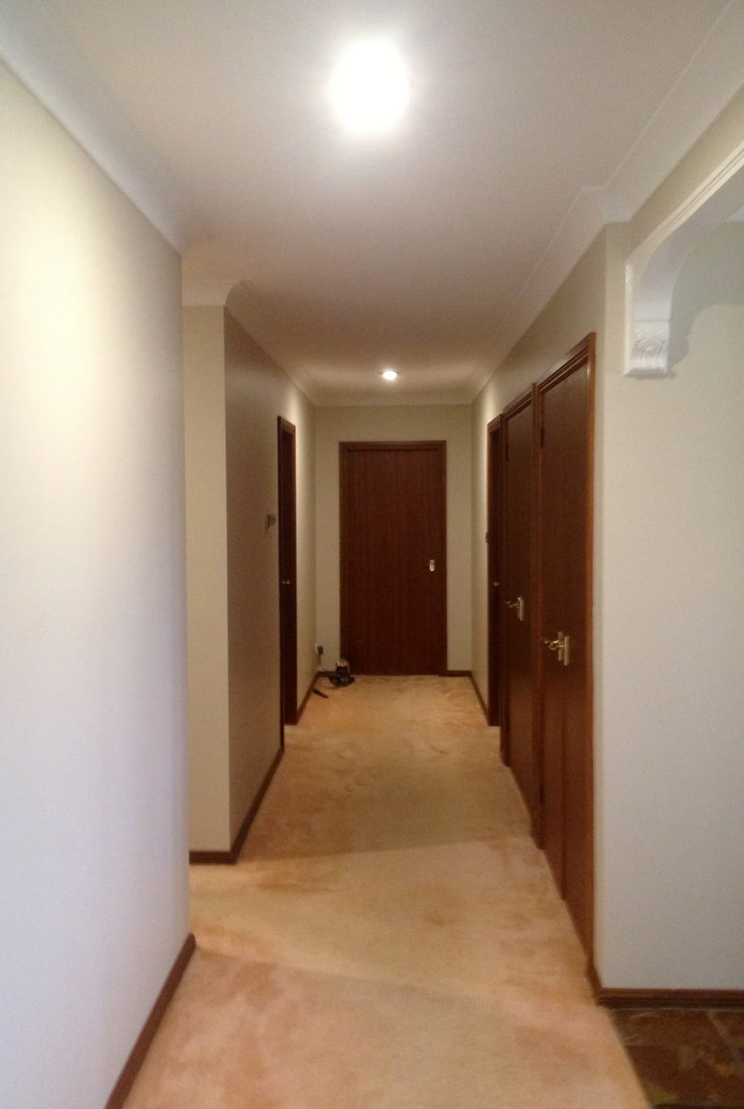 Hallway with white walls and dark doors