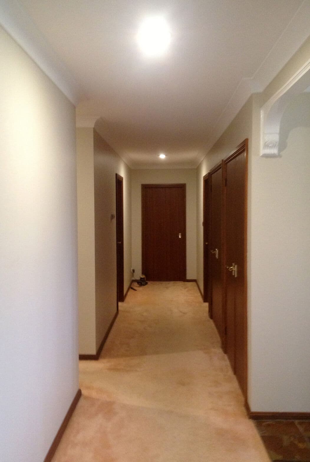 Hallway with white walls and dark doors