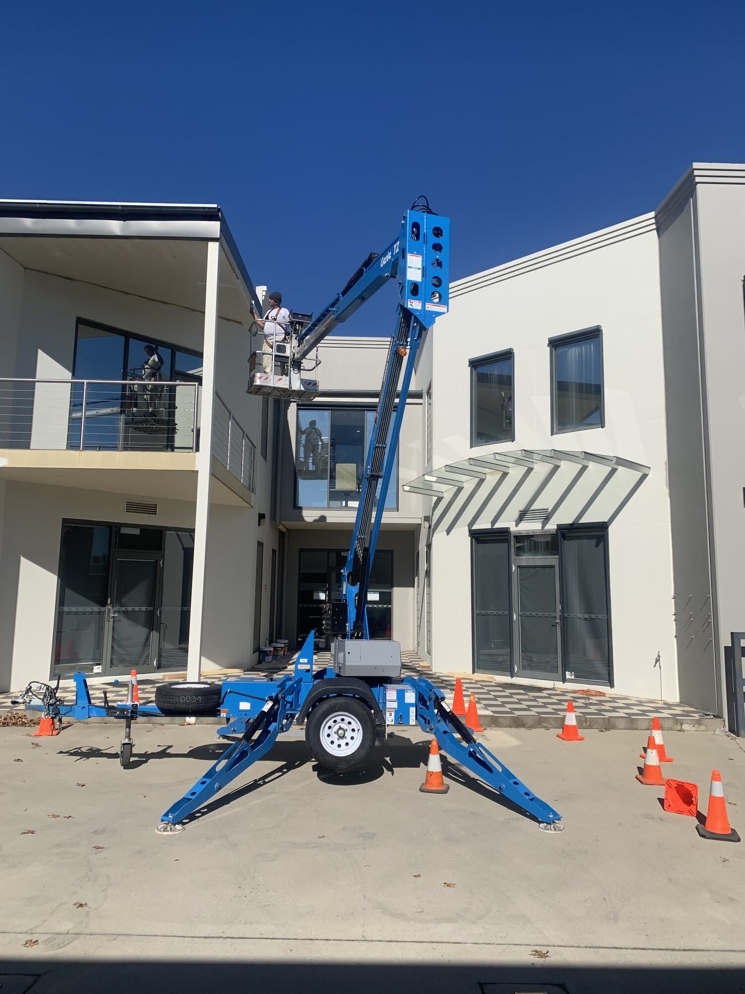 Two storey commercial exterior being repainted from a towable spider lift with the work area coned off, Murrays Painting, Orange NSW