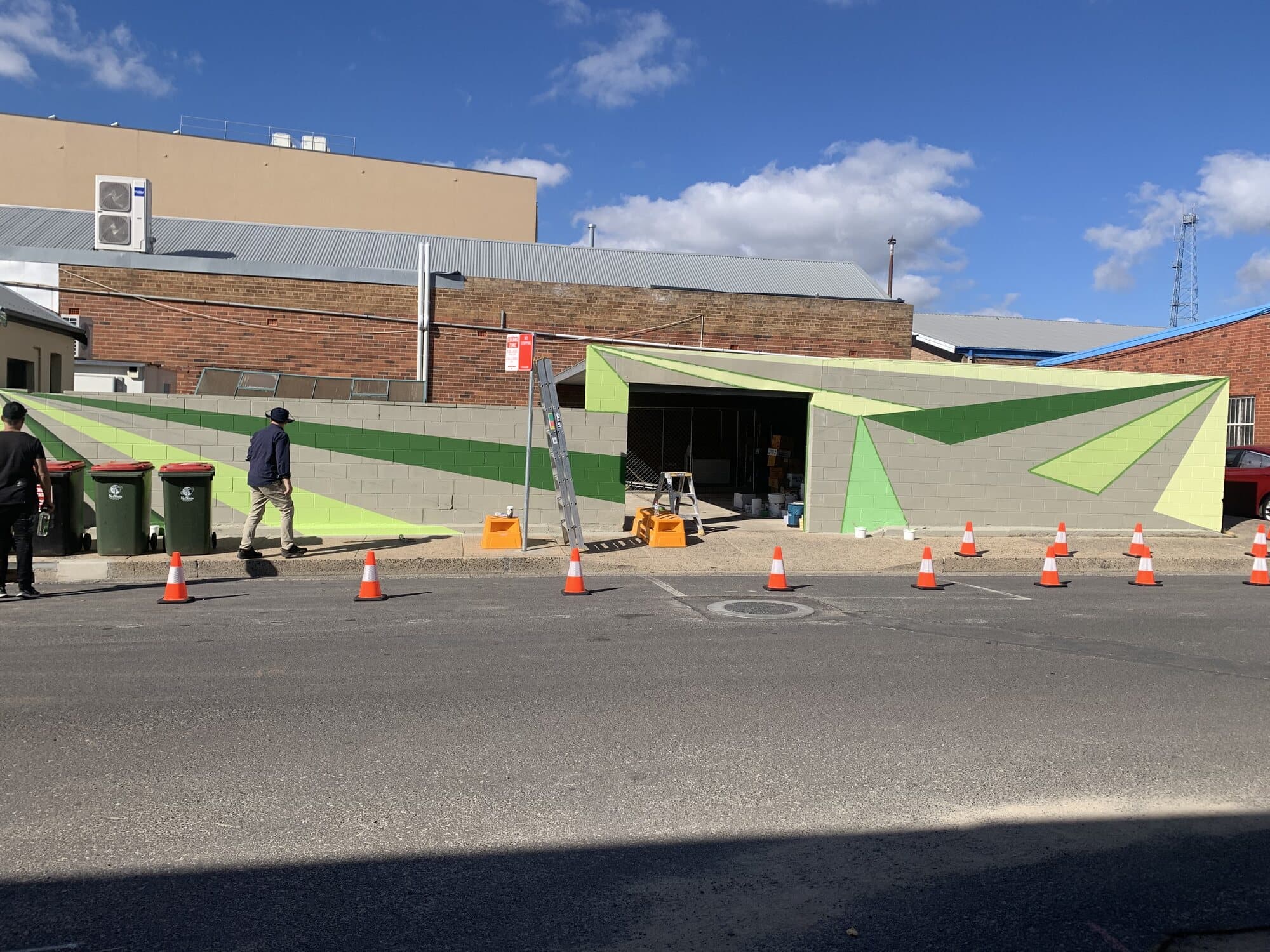 Large geometric mural painted across a besser block wall as public art for Orange City Council