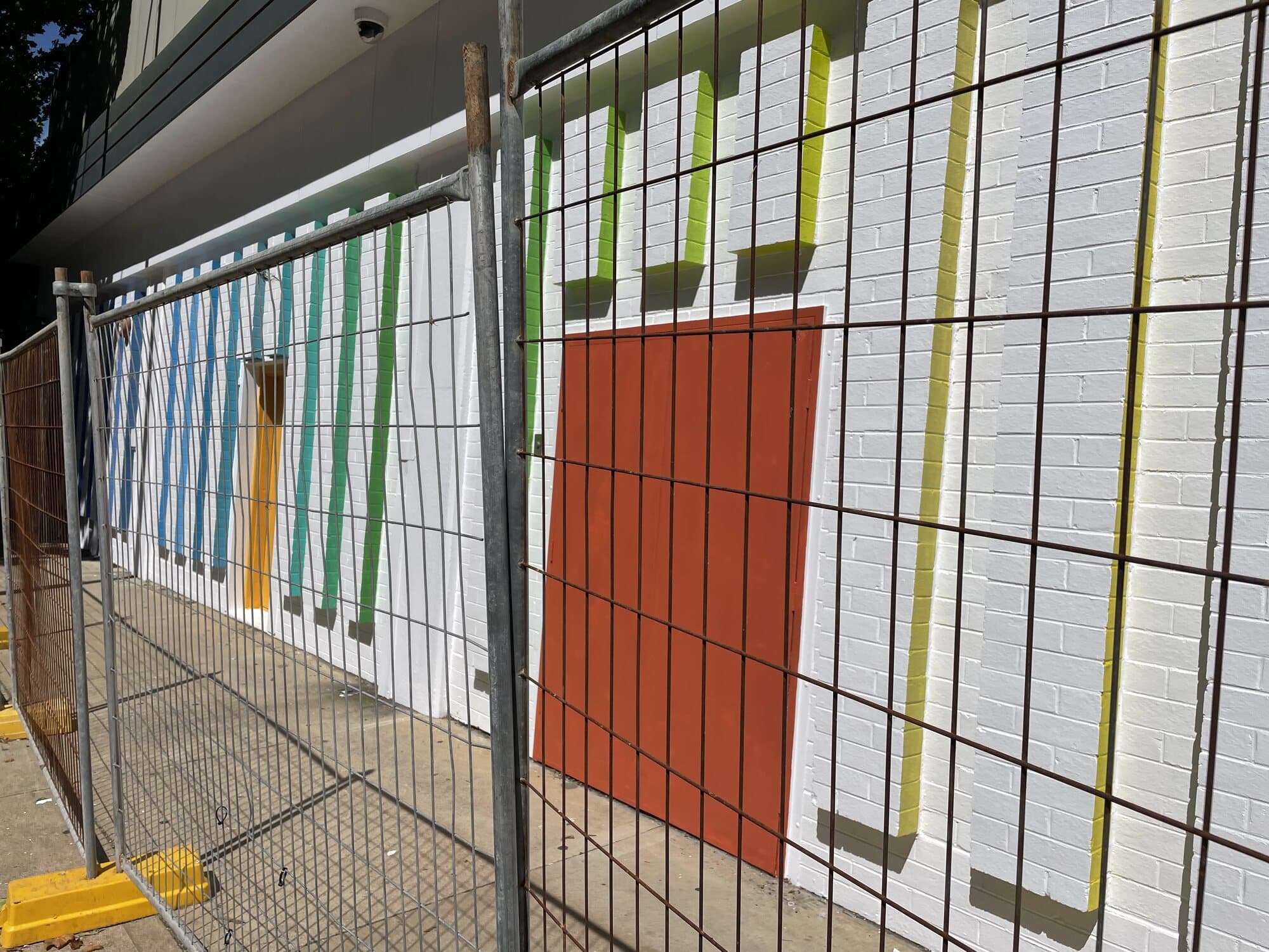 Rainbow stripe treatment painted on a white brick wall at a taxi rank as public art for Orange City Council