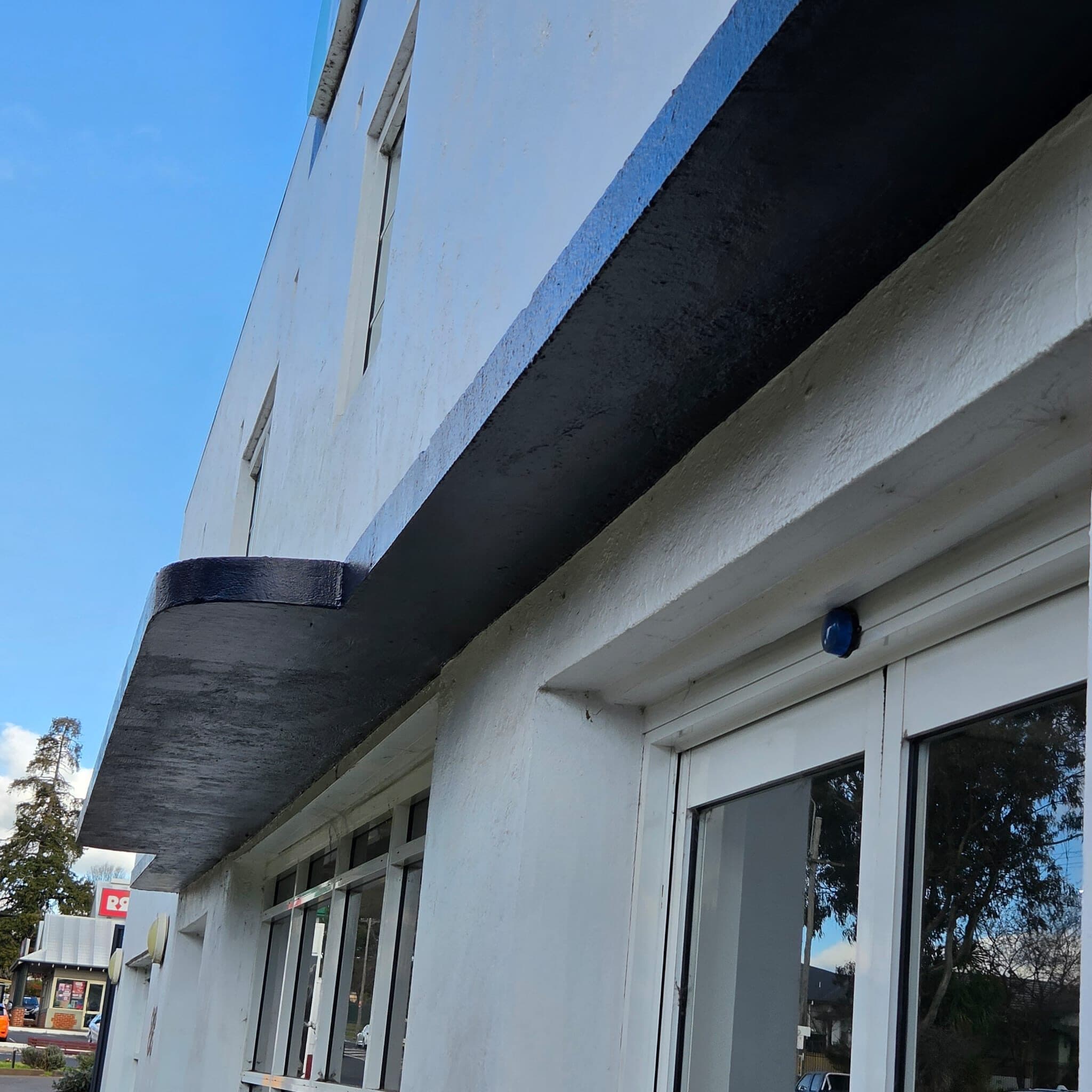 Charcoal awning fascia running the length of a white rendered shopfront in Orange NSW