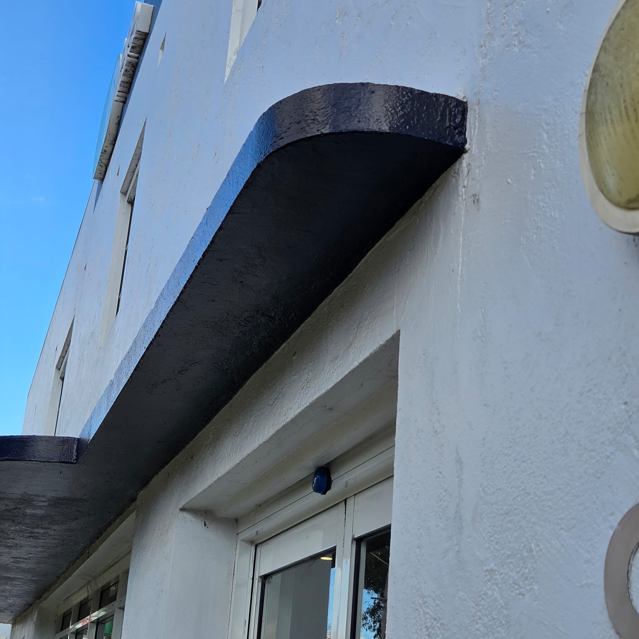 Curved return of a repainted awning where it meets the rendered wall of a commercial building in Orange NSW