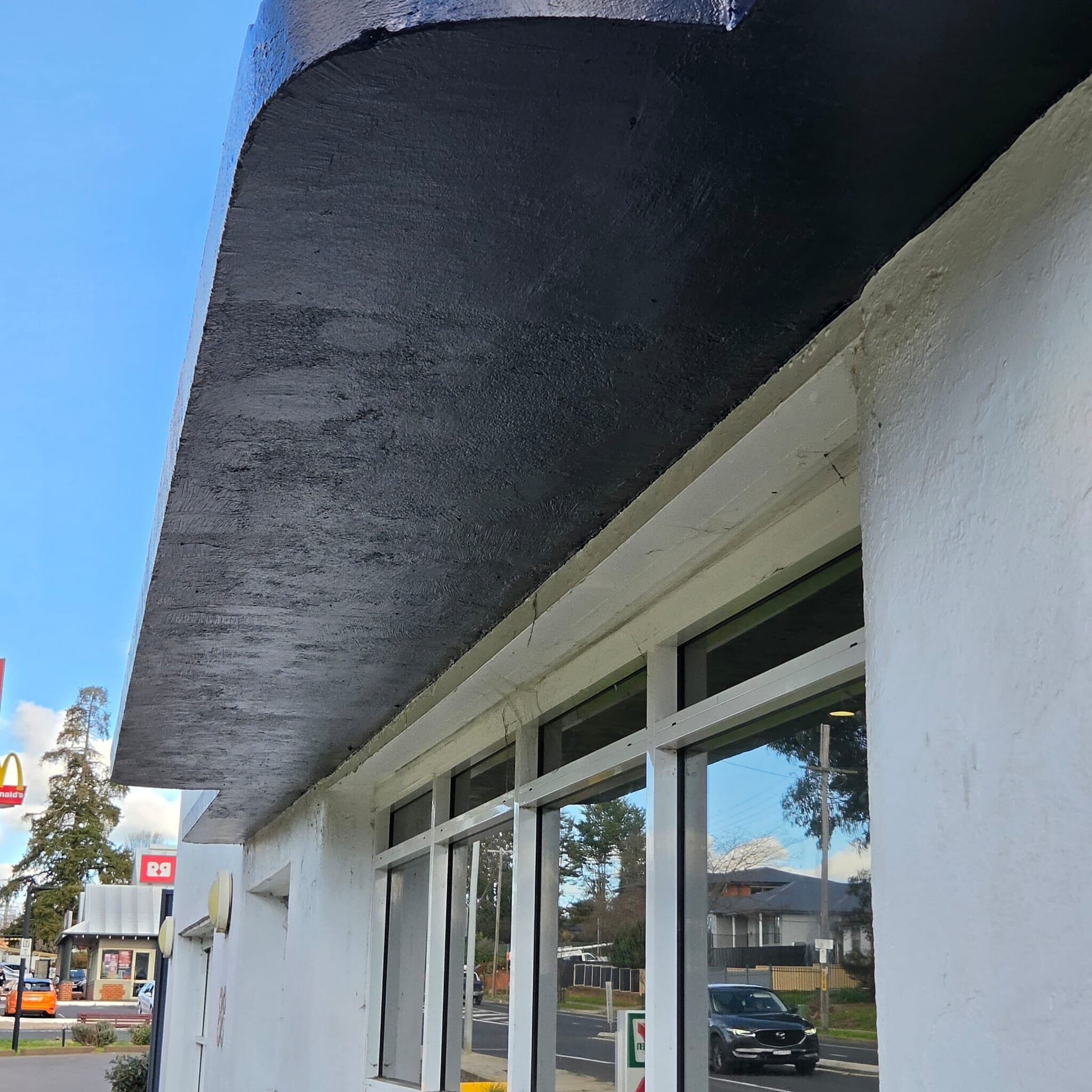 Underside of a cantilevered concrete awning repainted charcoal on a commercial building in Orange NSW