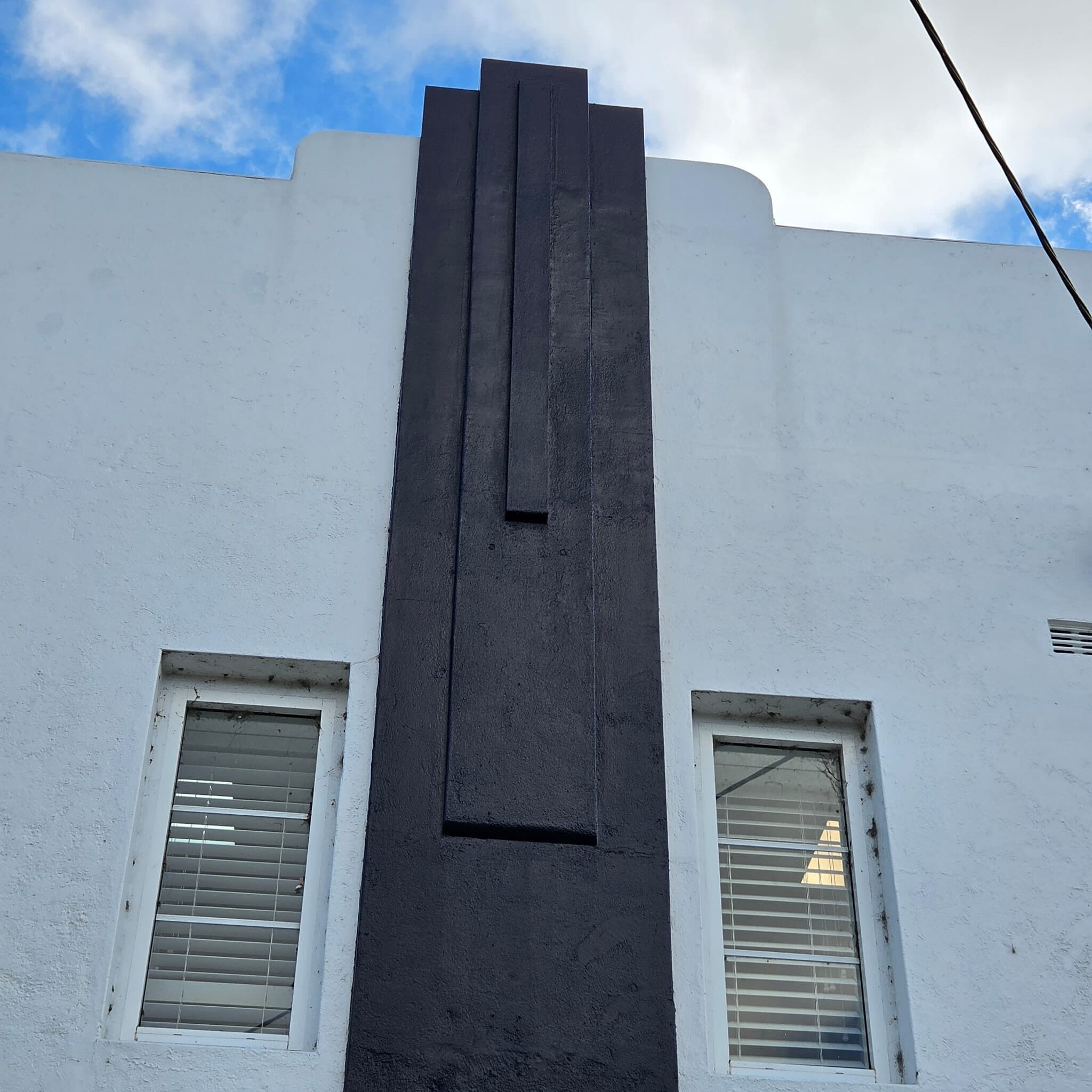 Stepped Art Deco pilaster picked out in charcoal against white render on a commercial facade in Orange NSW