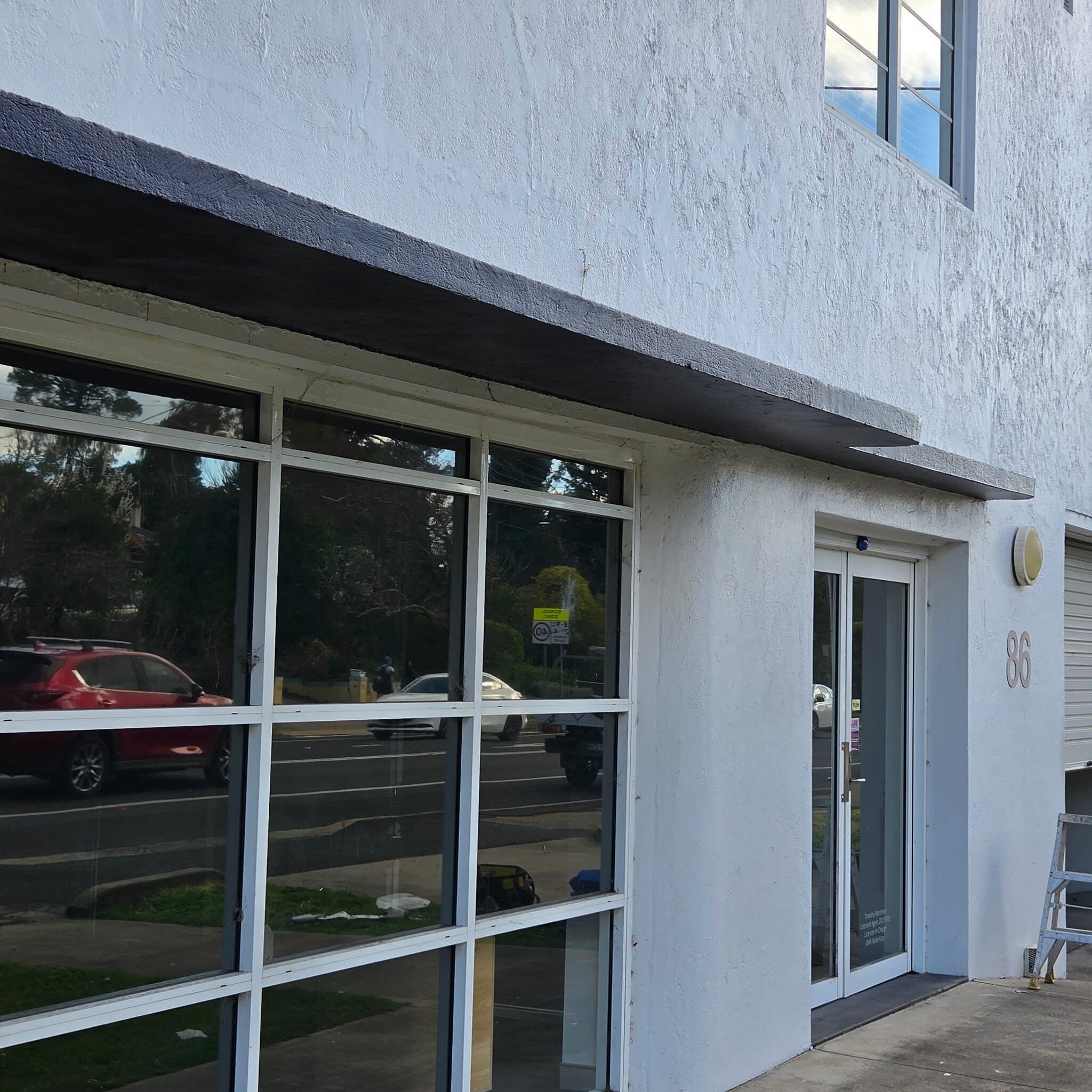 Repainted interwar commercial building in Orange NSW, white rendered walls with a charcoal awning and entry, seen from the street