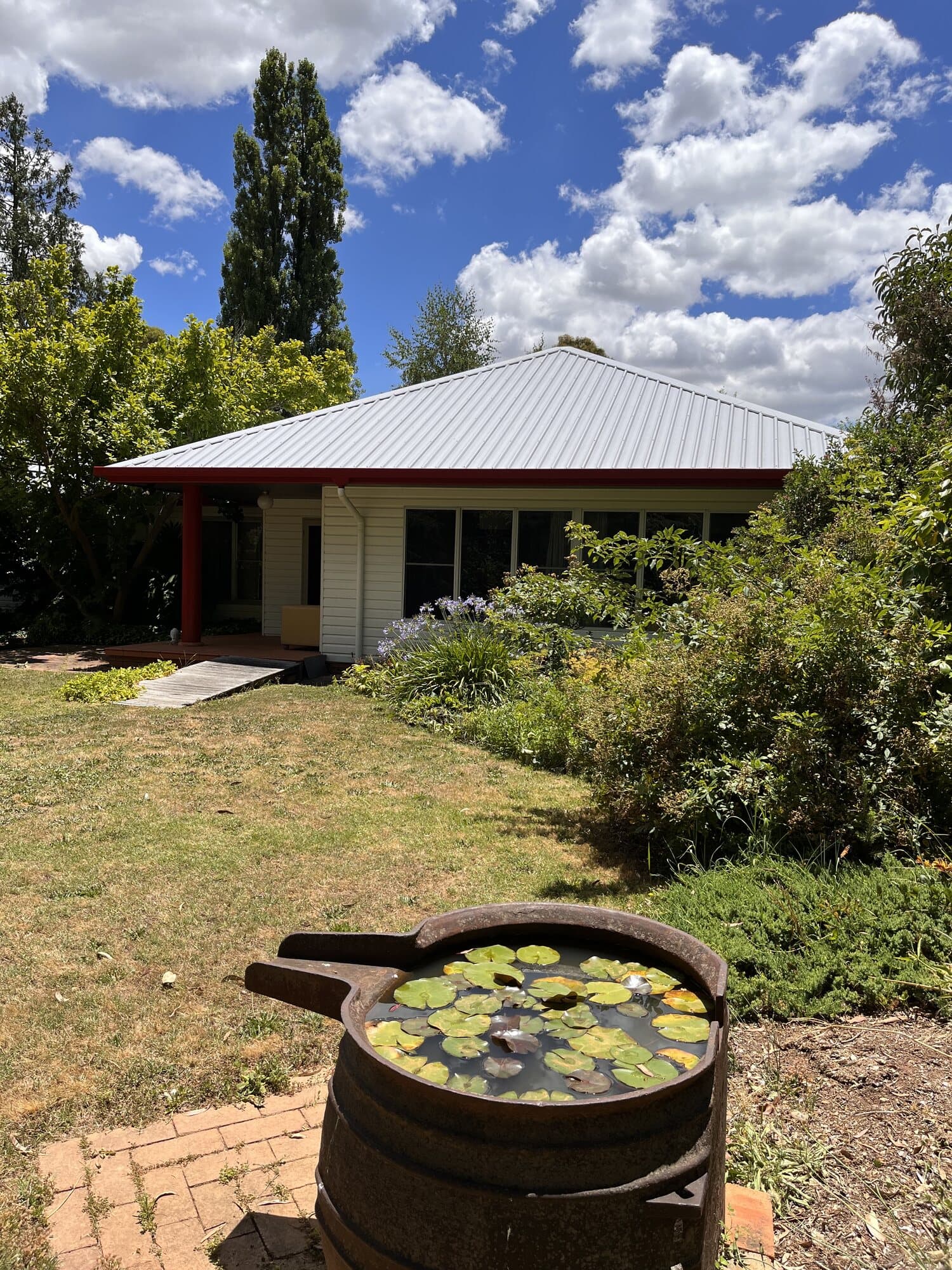 Weatherboard cottage with a freshly coated silver grey corrugated roof and red fascia, gutter and verandah post, by Murrays Painting, Orange NSW