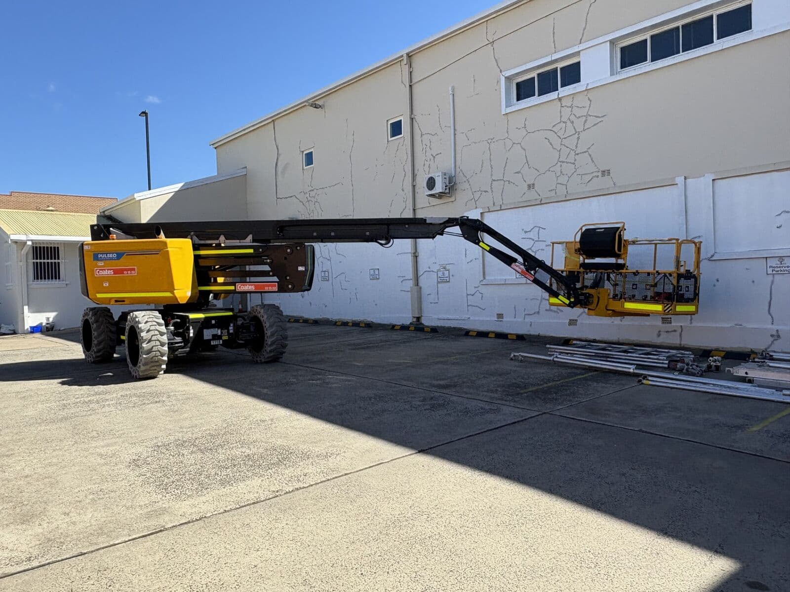 Boom lift against a rendered wall with crack repairs patched ready for coating by Murrays Painting, Orange NSW