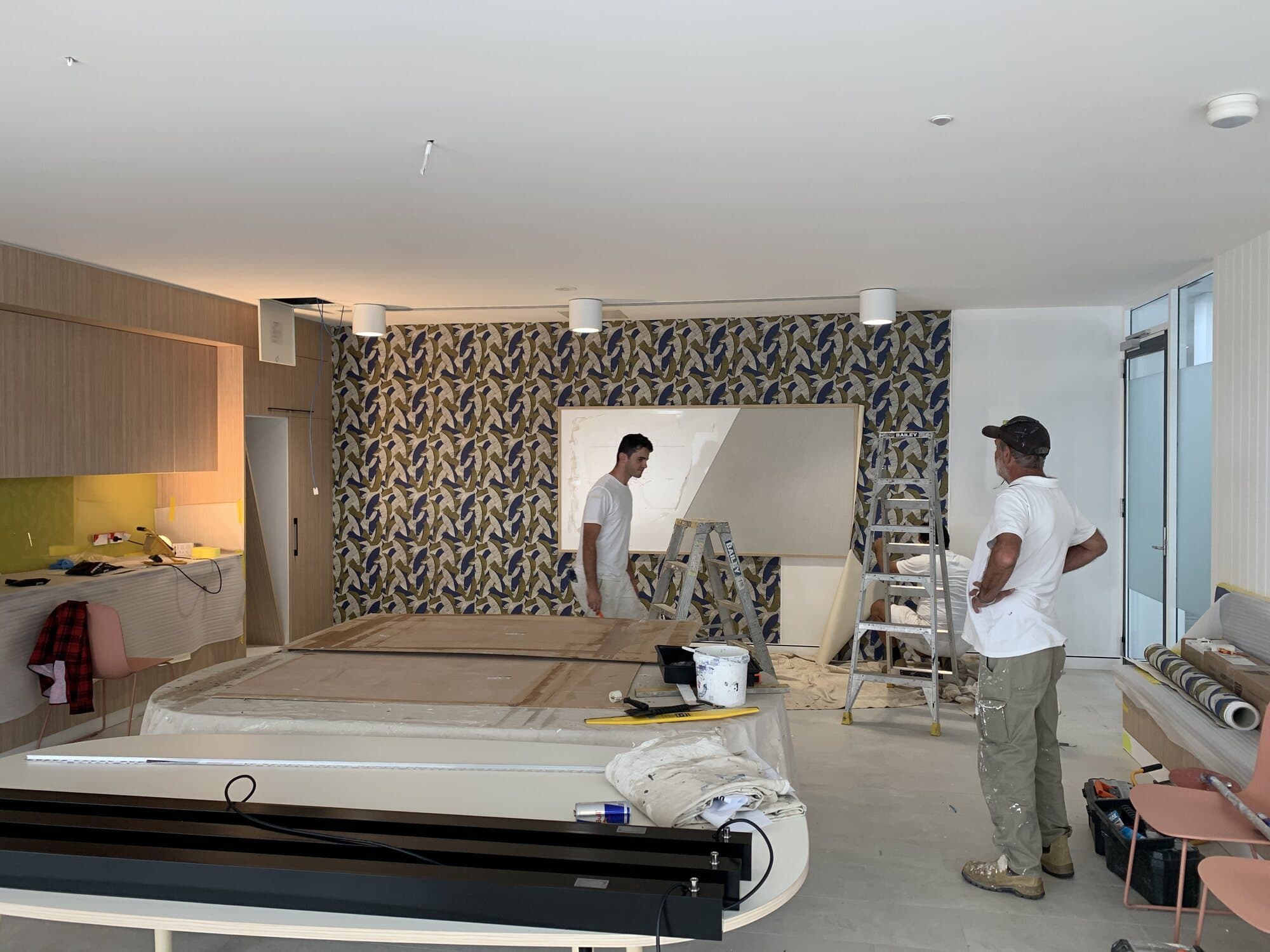 Botanical patterned wallpaper being hung across a full feature wall during an interior fitout by Murrays Painting, Orange NSW