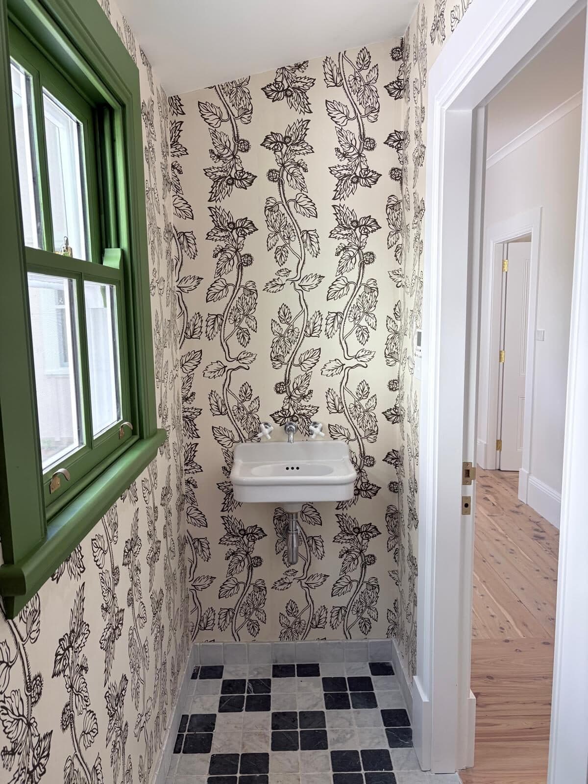 Powder room papered by Murrays Painting in a black and cream botanical trailing print, with the sash window and architraves painted deep green, Central West NSW